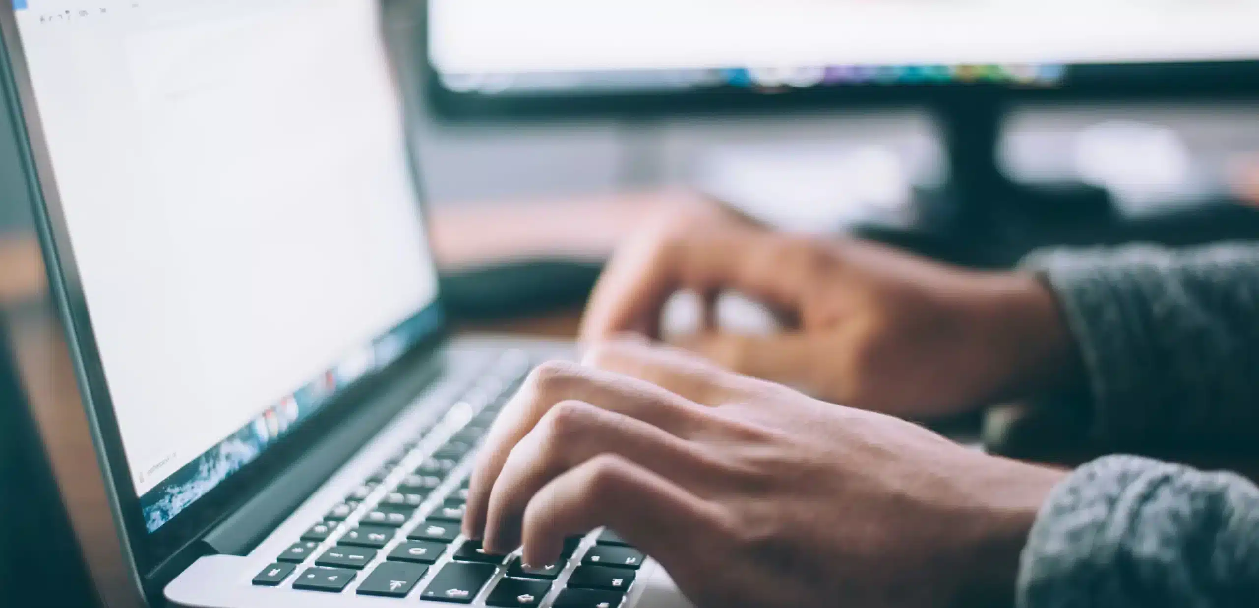 un homme tapant sur son clavier pour rechercher les avantages d'un logiciel de bilan carbone