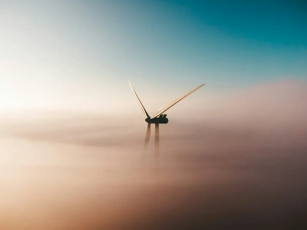 Éolienne émergeant d'une mer de brouillard au crépuscule